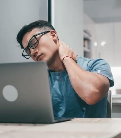 joven trabajando frente al monitor con dolor de cuello