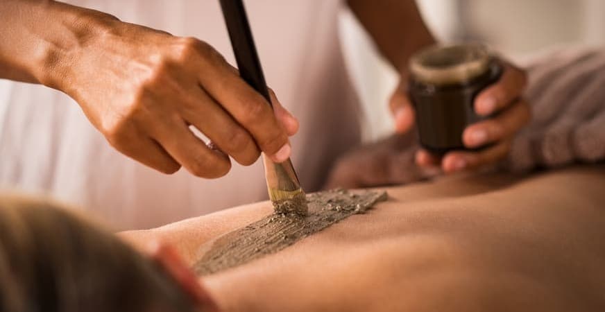 chica sentada en cama con dolor de cervicales